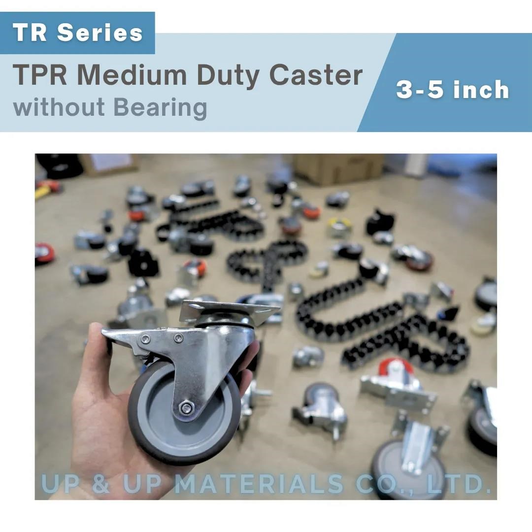 Hand holding gray TPR caster in workshop with other wheels in background, UP&UP Casters
